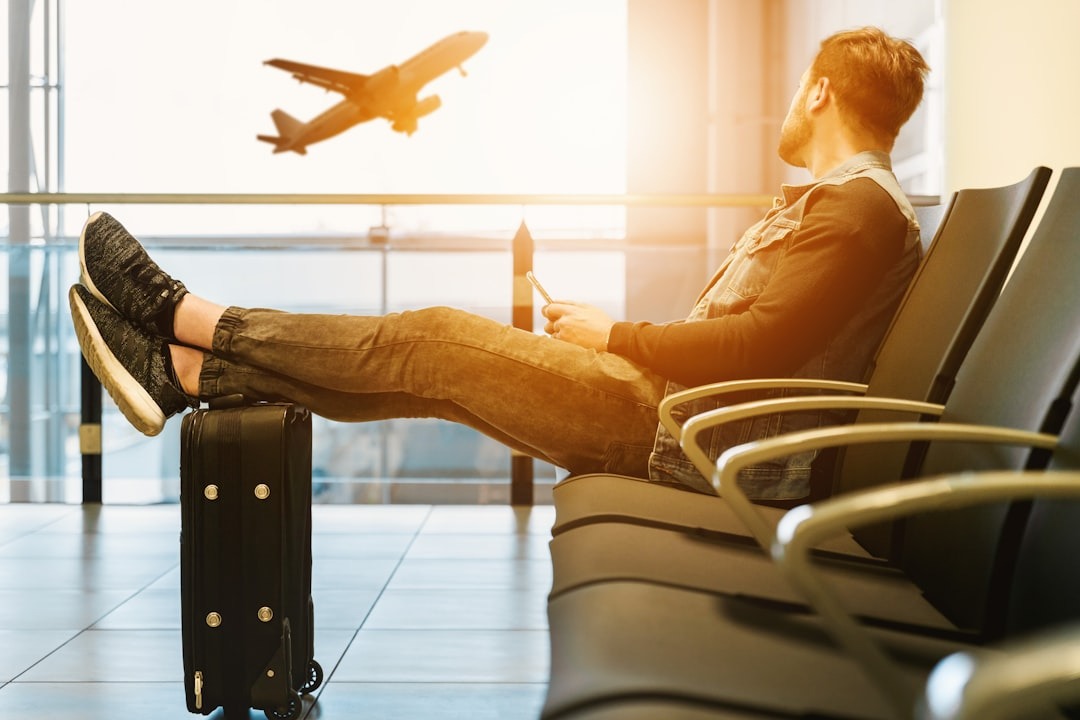 Man relaxing in airport lounge watching plane take off through the window