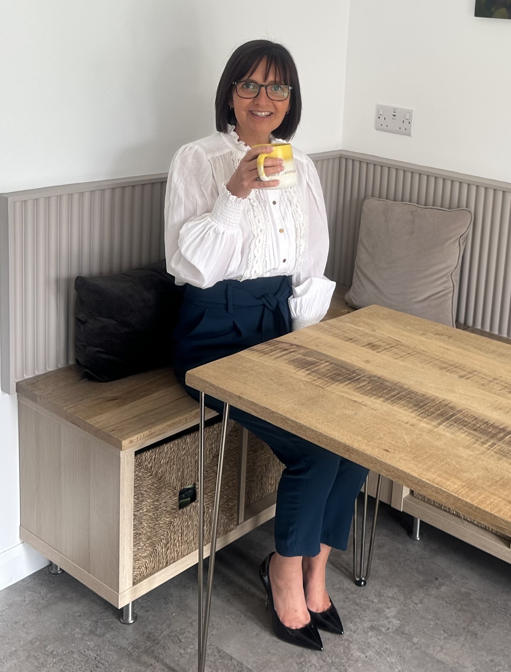 Tracey Burkinshaw Virtual Assistant sitting in the kitchen with a mug of coffee